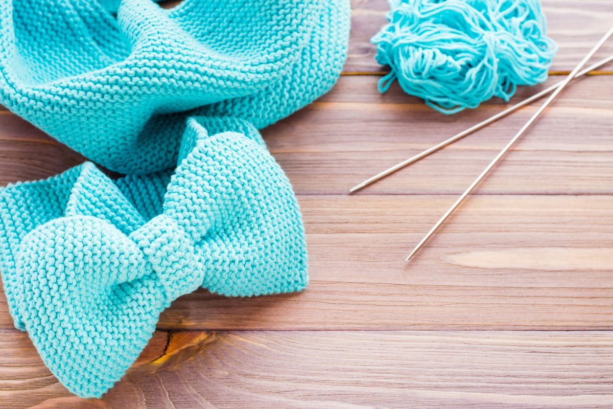 Knitted mint headband, snud, needles and tangle on a wooden table